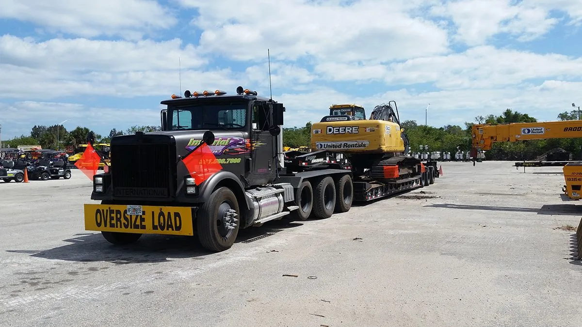 Imperial Towing oversize-load lowboy hauling a Deere excavator across Florida