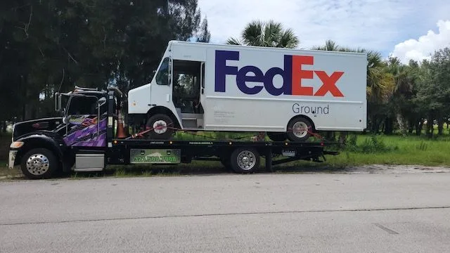 Imperial Towing flatbed assisting a FedEx box truck in Brevard County